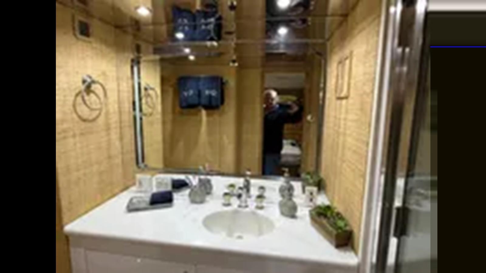 a person taking a picture of himself in a bathroom mirror aboard 1999 HATTERAS 74 SPORT DECK MOTOR YACHT Yacht for Sale