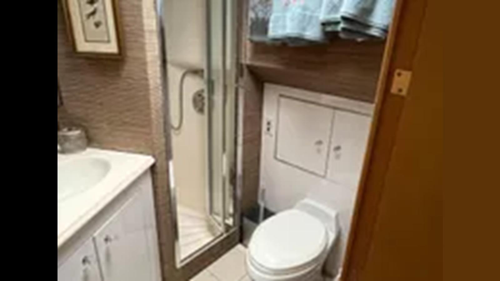 a bathroom with a toilet and a shower aboard 1999 HATTERAS 74 SPORT DECK MOTOR YACHT Yacht for Sale