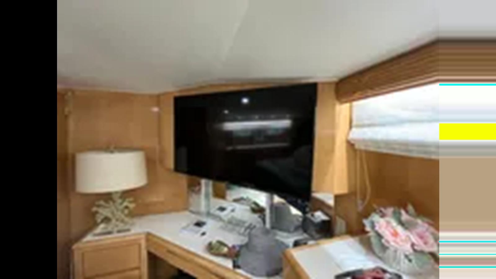 a room with a television and a lamp aboard 1999 HATTERAS 74 SPORT DECK MOTOR YACHT Yacht for Sale