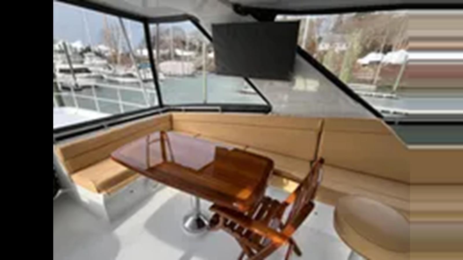 a table with chairs on it aboard 1999 HATTERAS 74 SPORT DECK MOTOR YACHT Yacht for Sale