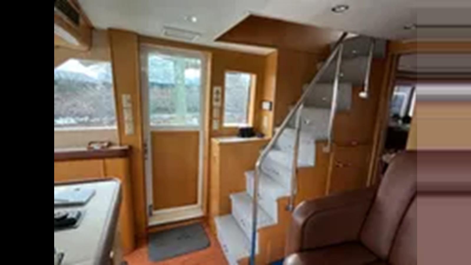 a room with a couch and a ladder aboard 1999 HATTERAS 74 SPORT DECK MOTOR YACHT Yacht for Sale