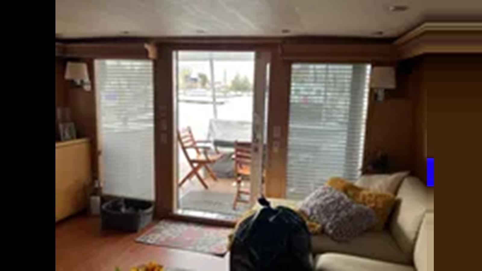 a living room with a couch and a window aboard 1999 HATTERAS 74 SPORT DECK MOTOR YACHT Yacht for Sale