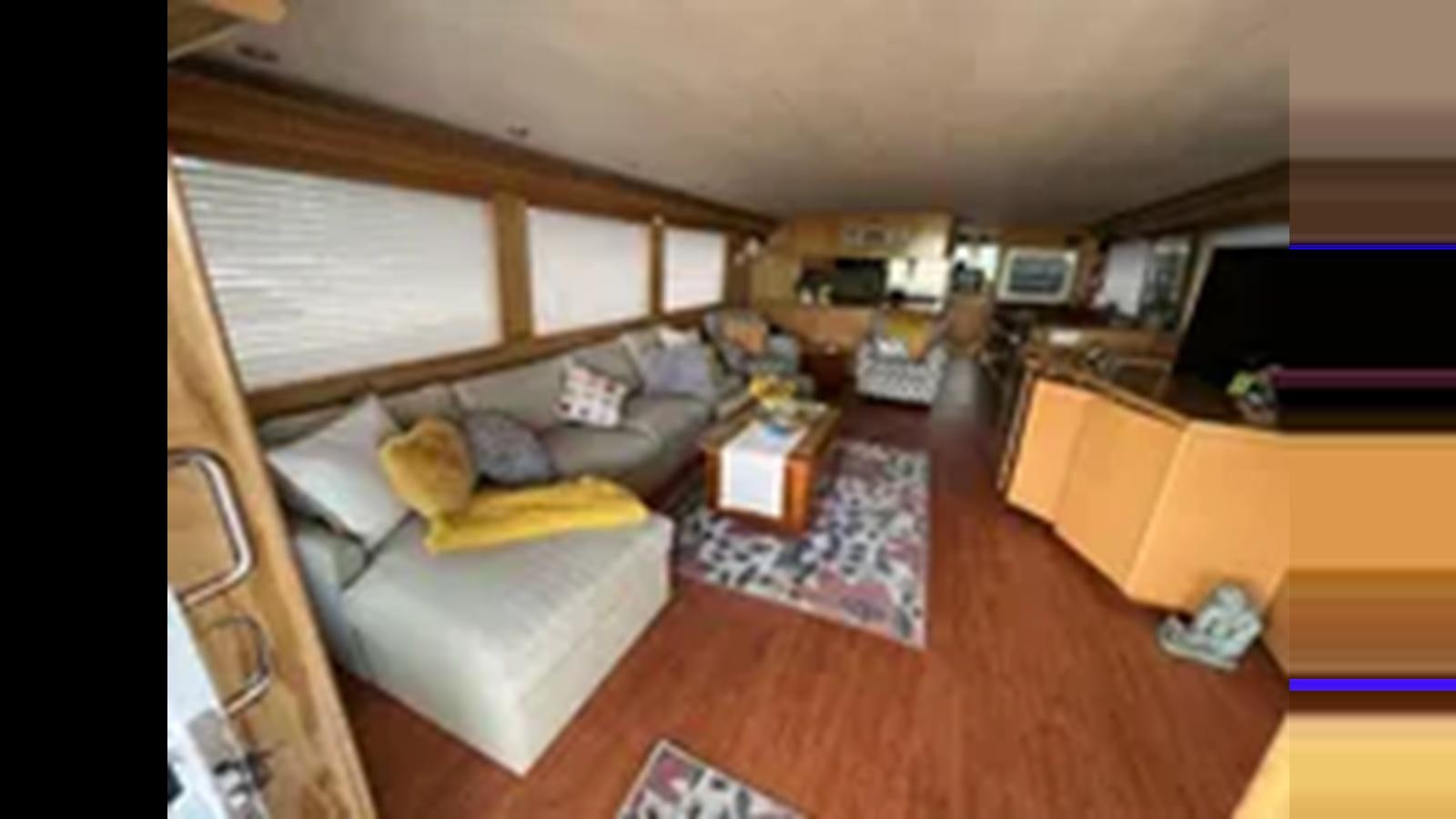 a living room with a couch and a tv aboard 1999 HATTERAS 74 SPORT DECK MOTOR YACHT Yacht for Sale