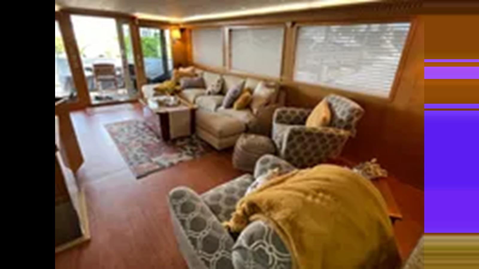 a living room with a couch and a window aboard 1999 HATTERAS 74 SPORT DECK MOTOR YACHT Yacht for Sale