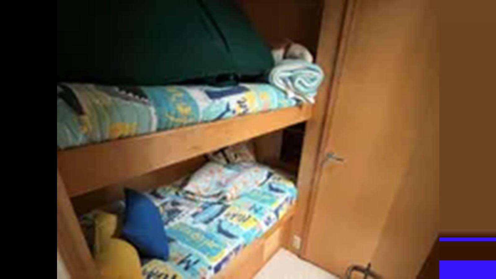 a bed with clothes on it aboard 1999 HATTERAS 74 SPORT DECK MOTOR YACHT Yacht for Sale