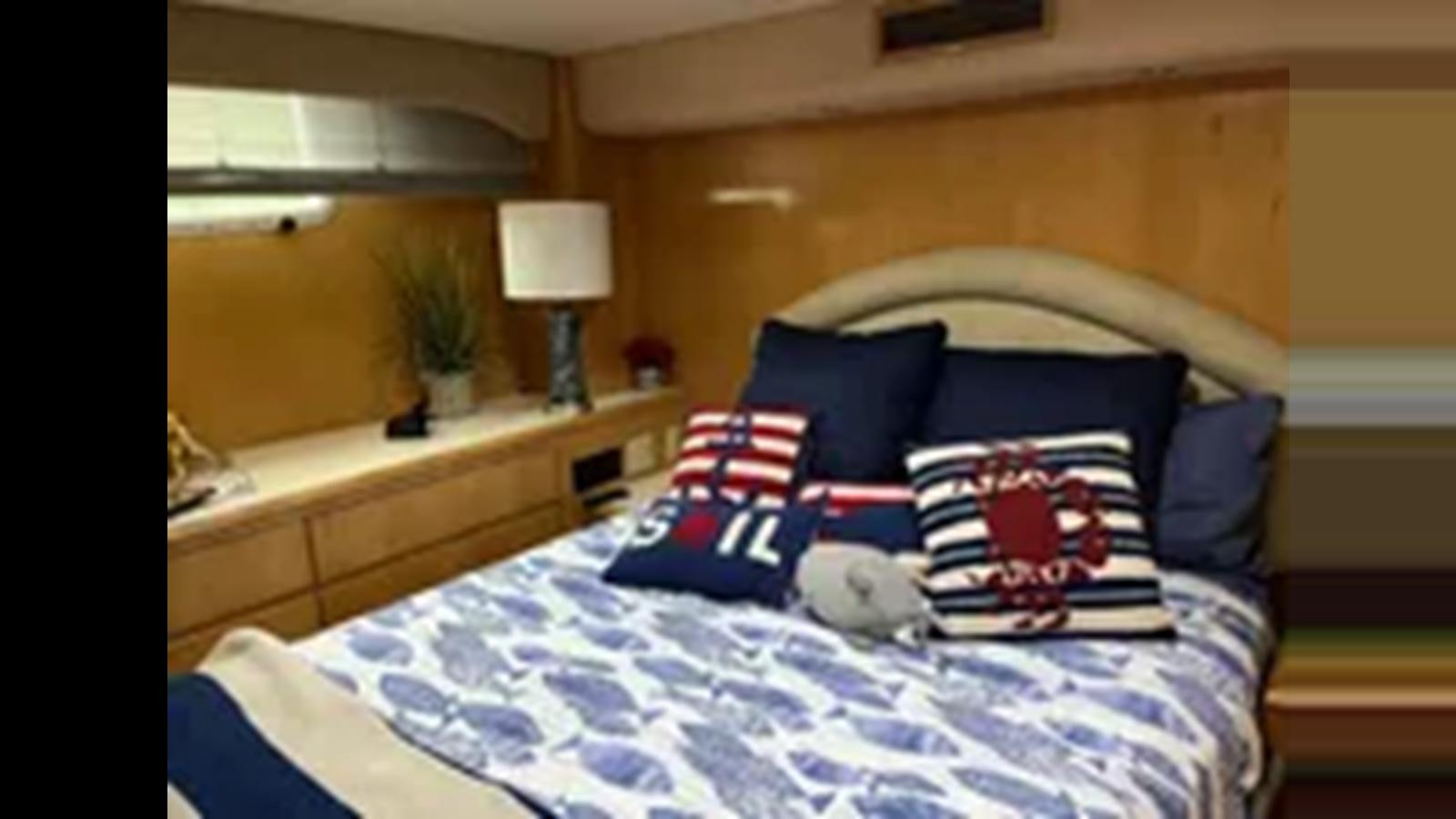 a bed with blue and white pillows aboard 1999 HATTERAS 74 SPORT DECK MOTOR YACHT Yacht for Sale