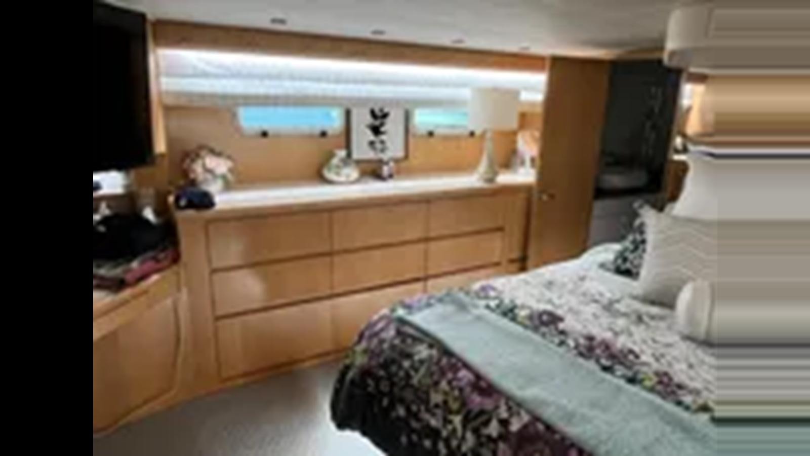a bedroom with a bed and a dresser aboard 1999 HATTERAS 74 SPORT DECK MOTOR YACHT Yacht for Sale