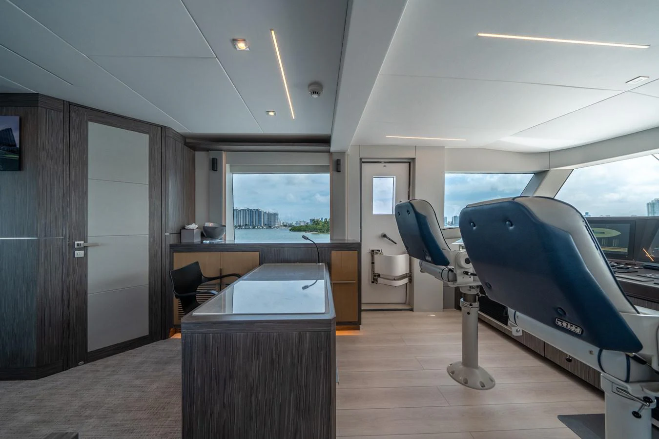 a room with a large window and a desk with a large blue chair aboard DAY ONE Yacht for Sale