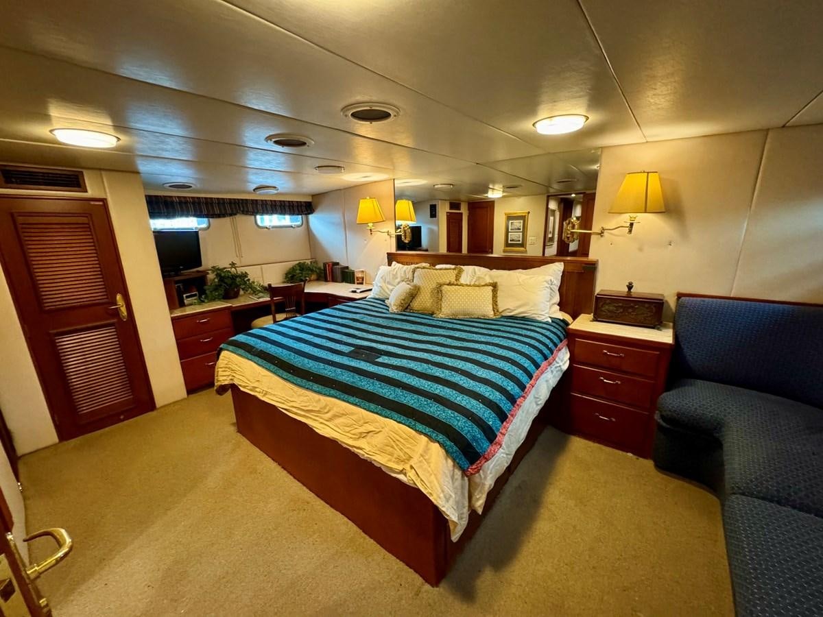 a bedroom with a bed and a chair aboard BRAVEHEART Yacht for Sale