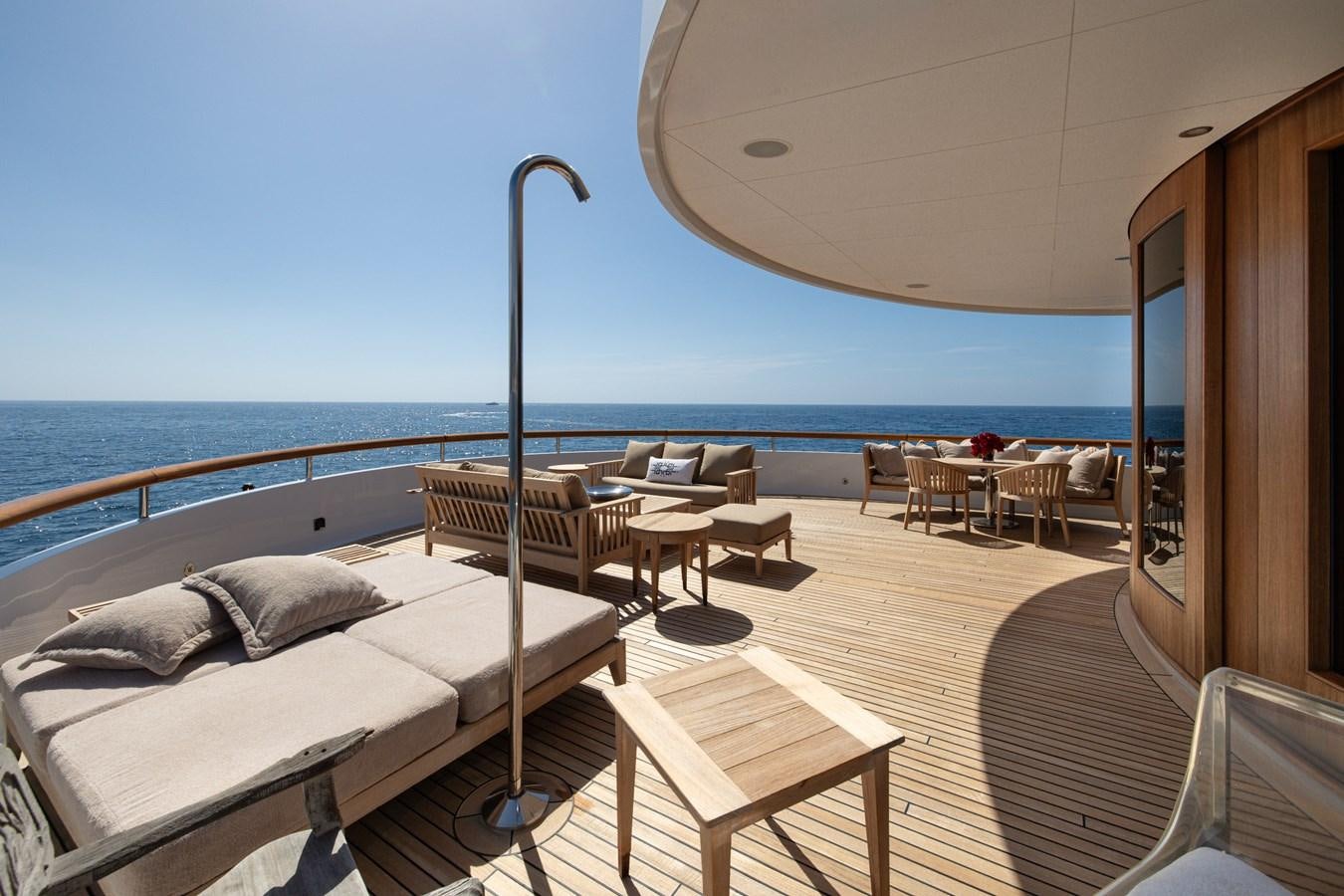 a room with a bed and a table and chairs on the deck aboard WEDGE TOO Yacht for Sale