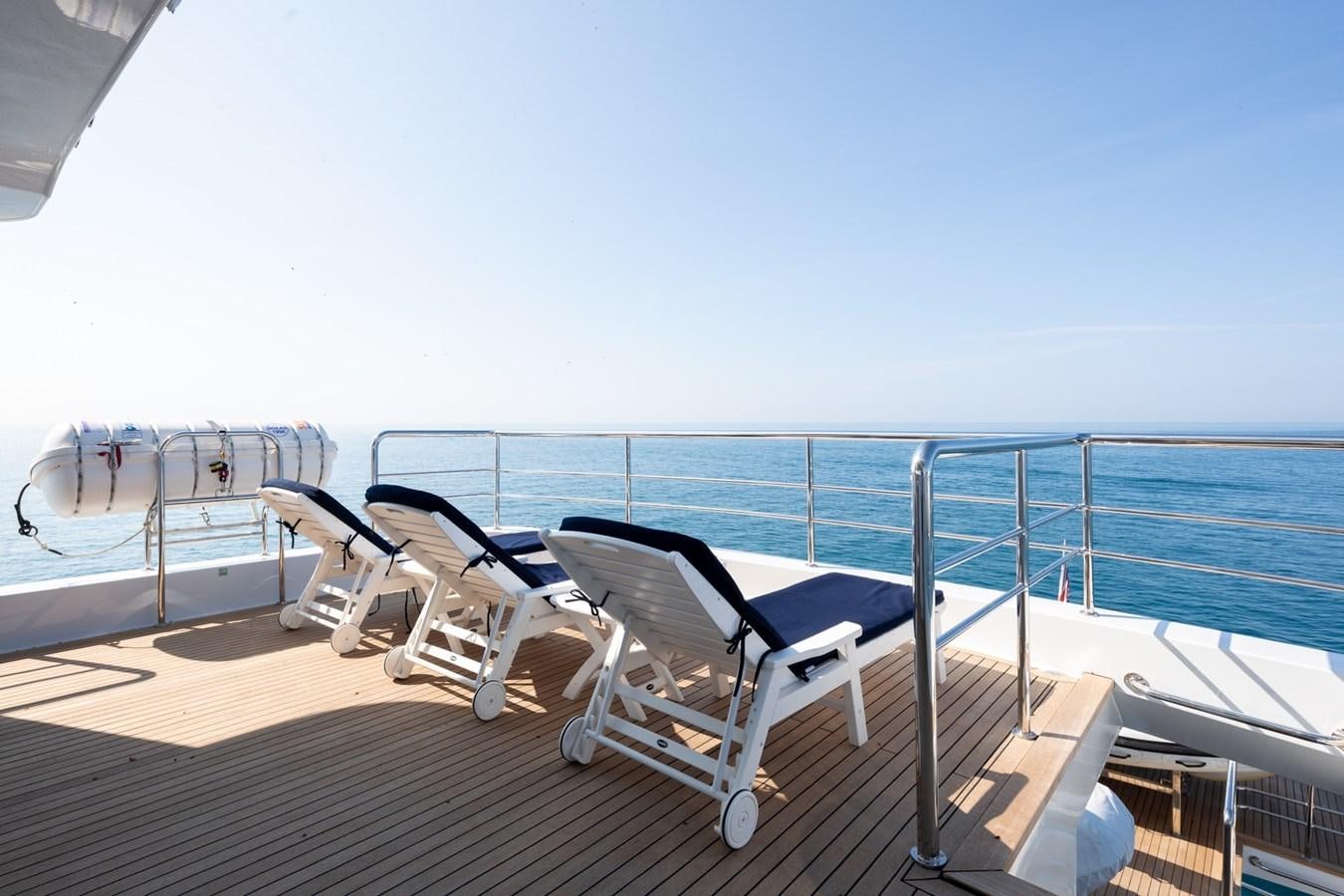 a deck with chairs and a body of water aboard BEYOND CAPRICORN Yacht for Sale