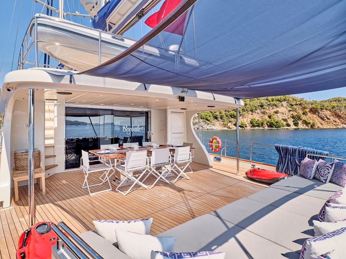 a deck with a pool and a deck with chairs and tables aboard BOOBALE Yacht for Sale