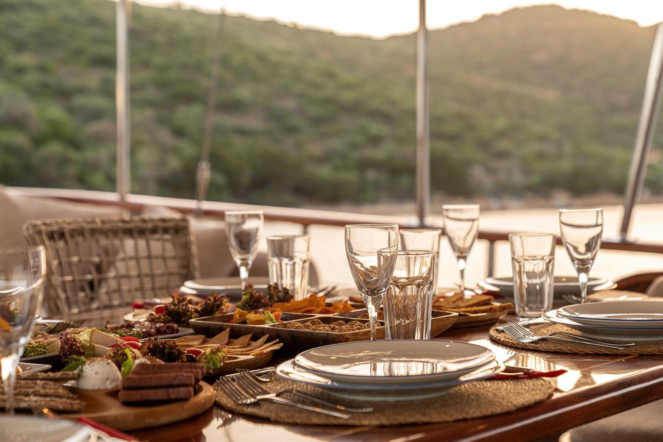 a table with food and wine glasses aboard L'ORIENT Yacht for Sale