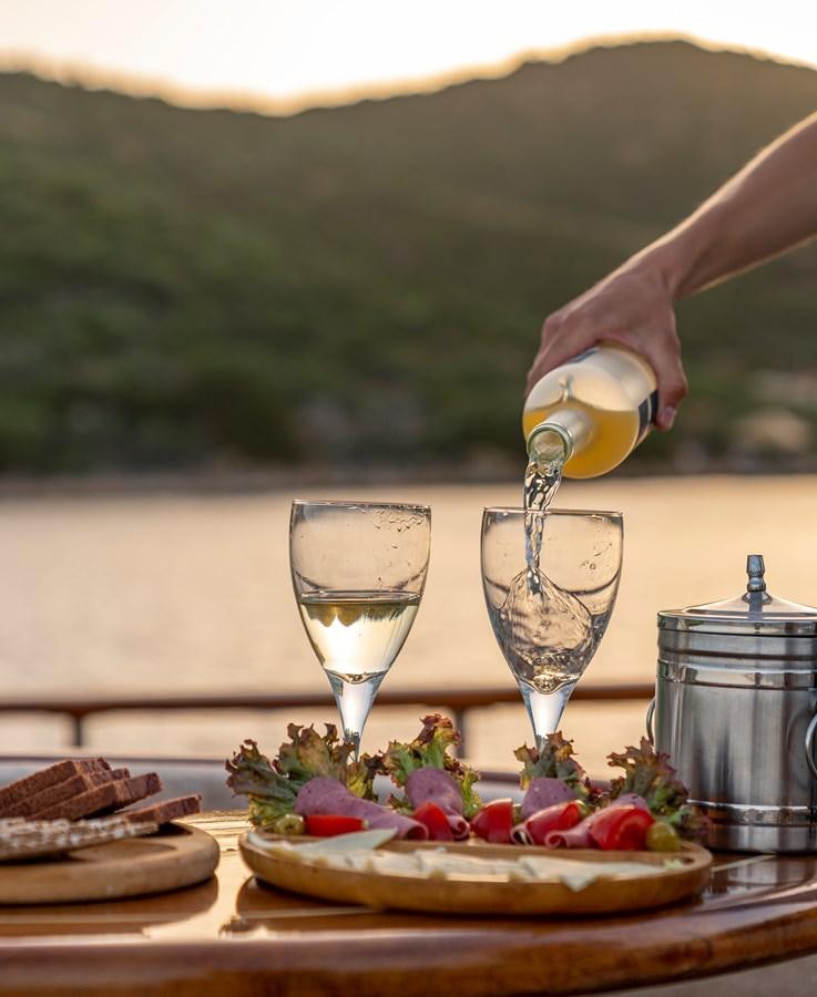 a person pouring wine into a glass aboard L'ORIENT Yacht for Sale