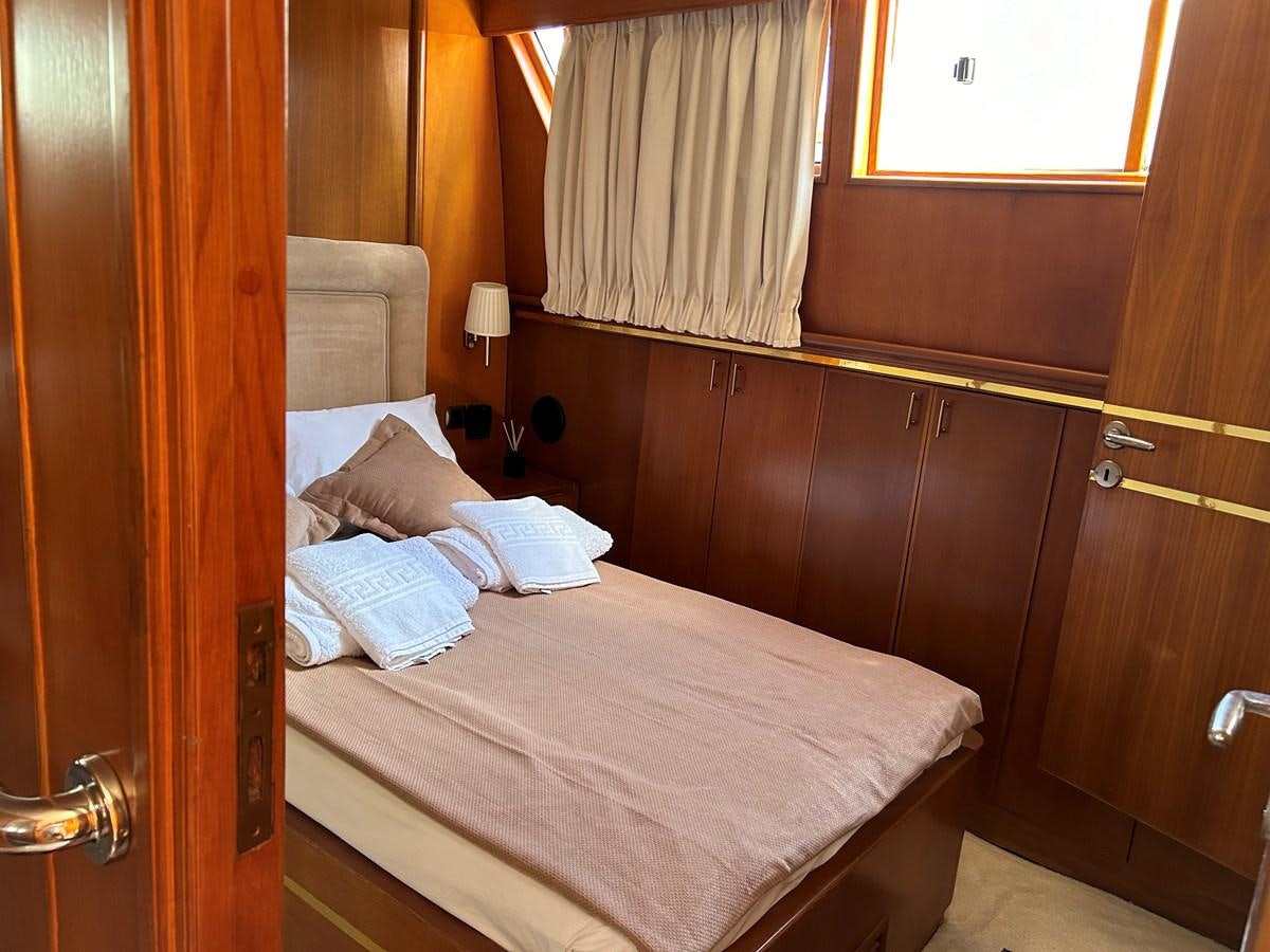 a bed with a wooden headboard aboard MOTORSAILLOR Yacht for Sale