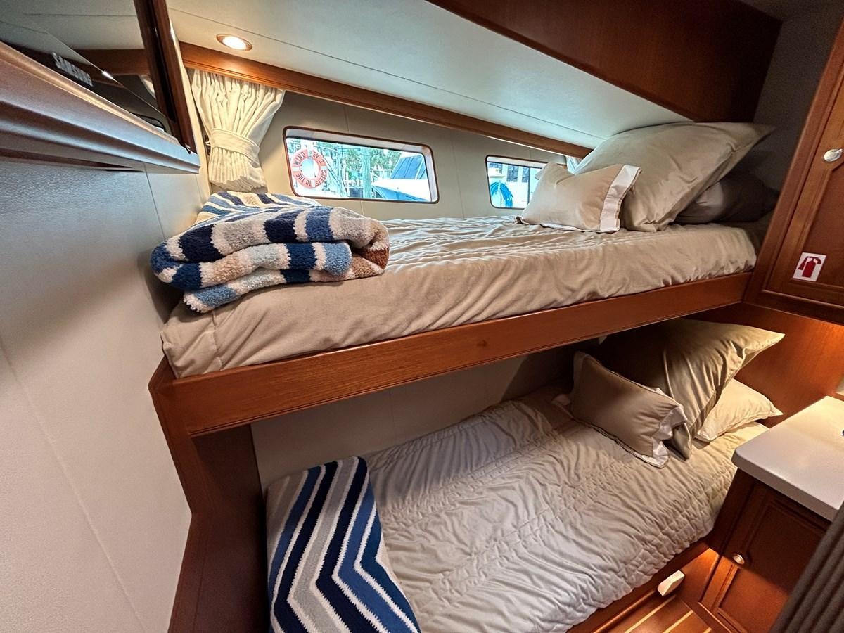a bed with a blue pillow and a blue stuffed animal on it aboard NOVIA II Yacht for Sale