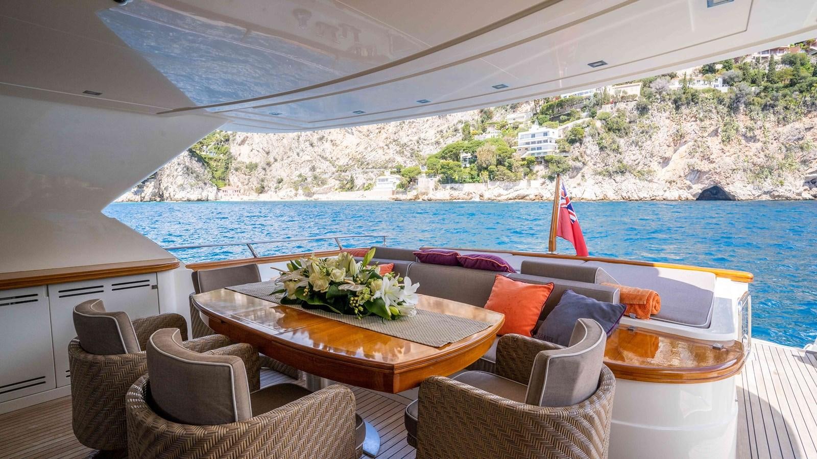 a table with chairs and a view of the ocean aboard ELEGANCE OF CANNES Yacht for Sale