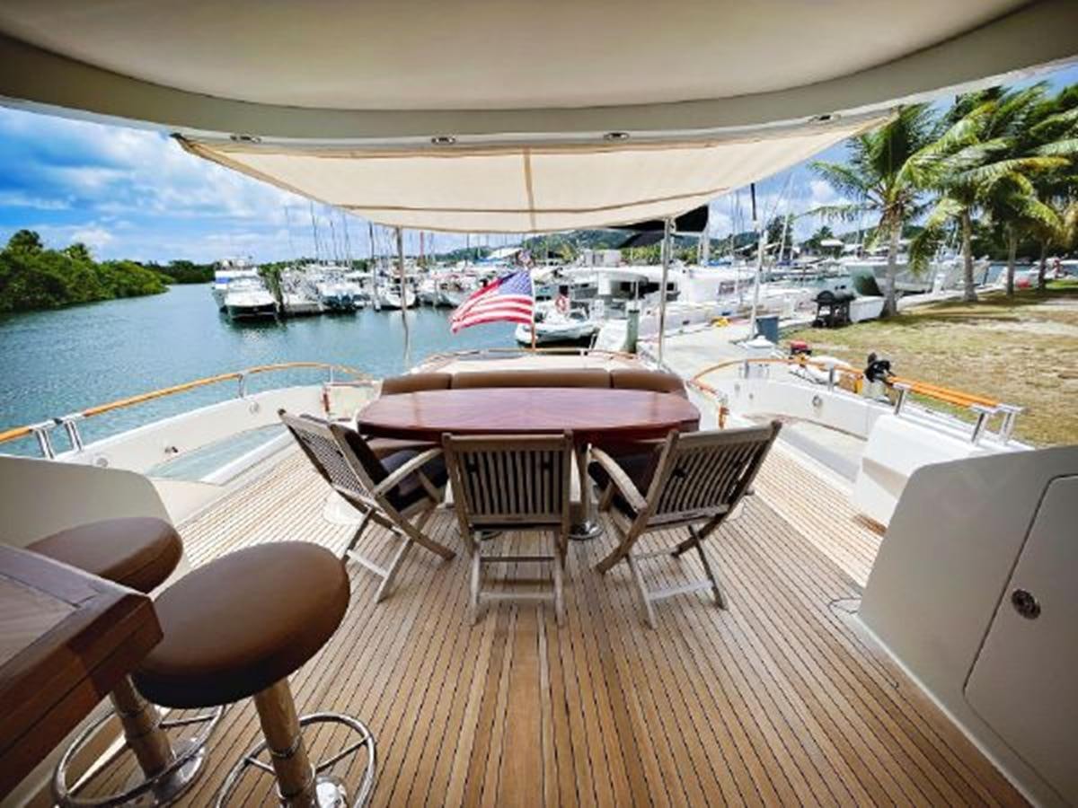 a deck with chairs and tables on it by a body of water aboard LOVIN LIFE Yacht for Sale