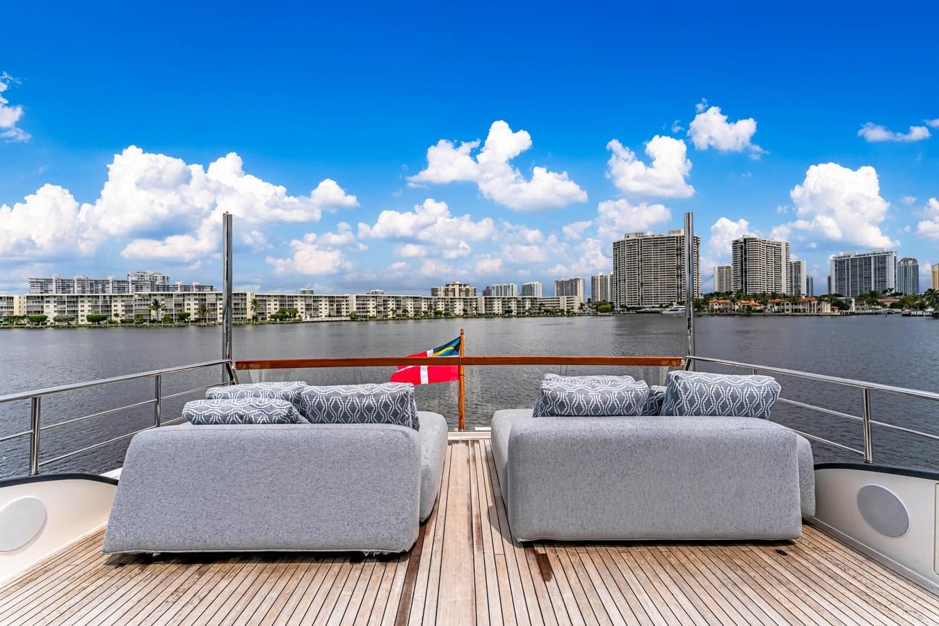a deck with couches and a city in the background aboard 2018 SANLORENZO SL78 Yacht for Sale