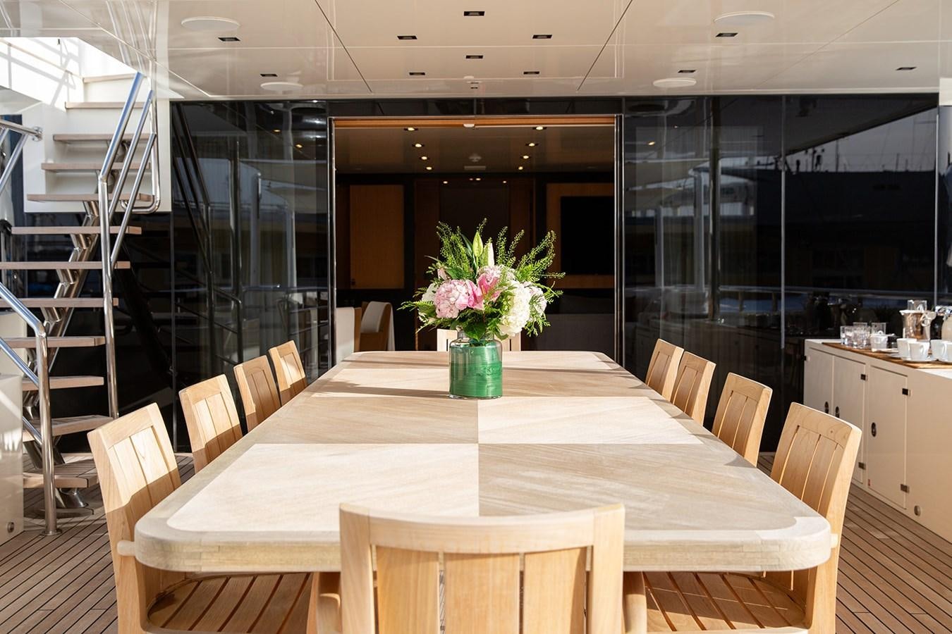 a dining table with chairs and a staircase in the background aboard BELONGERS Yacht for Sale