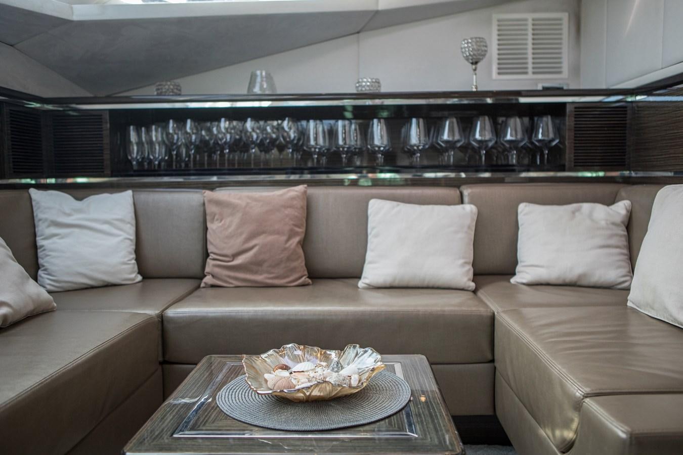 a couch with a glass display behind it aboard CLOUDS Yacht for Sale