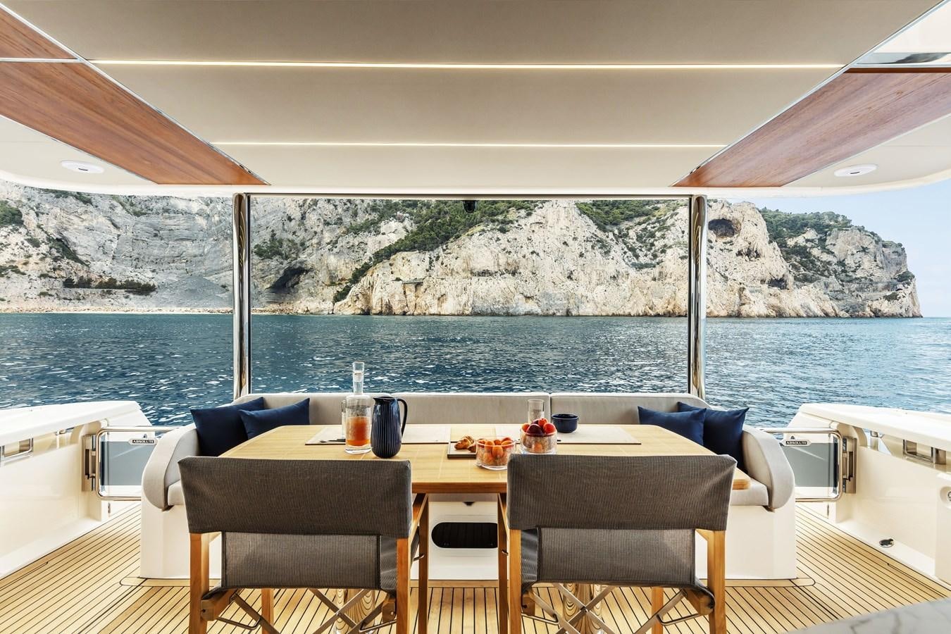 a table with chairs and a view of a body of water aboard 2025 ABSOLUTE NAVERTTA 68 Yacht for Sale