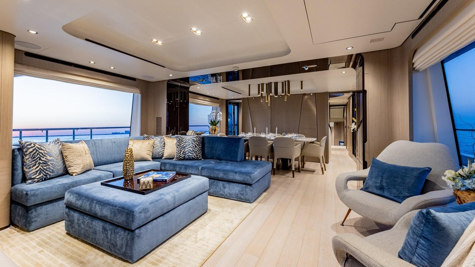 a living room with a blue couch and a large window aboard 4 PLAY Yacht for Sale