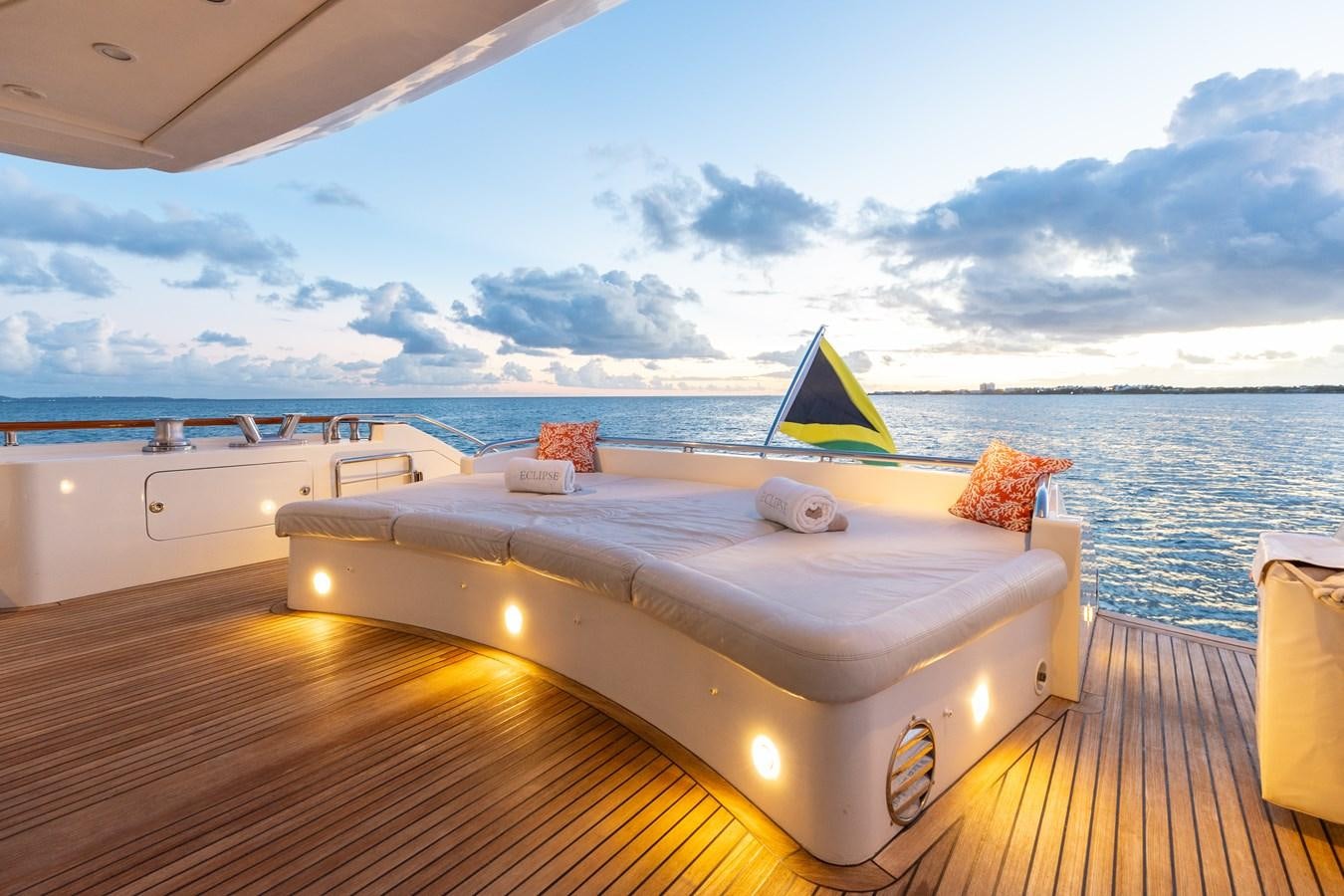 a large white bed with a green umbrella on a deck overlooking a large body of water aboard ECLIPSE Yacht for Sale