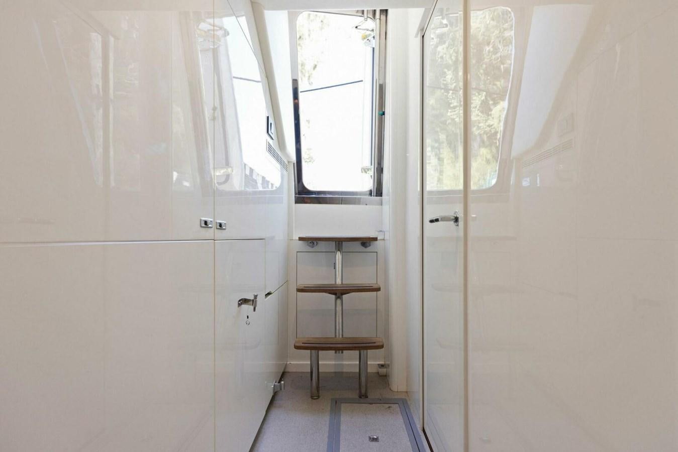 a white room with a shelf and a window aboard AMARULA SUN Yacht for Sale