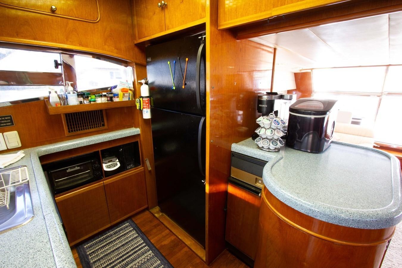 a kitchen with a black refrigerator aboard MADNESS Yacht for Sale