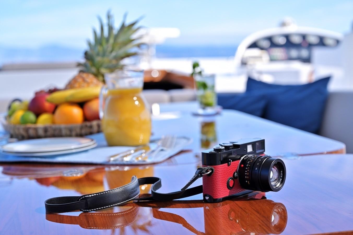 a camera and a camera on a table with a glass of orange juice aboard CLARITY Yacht for Sale