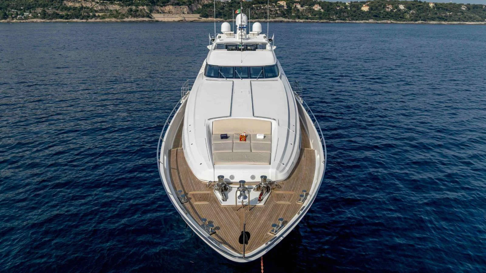 A sleek yacht is anchored on calm waters with a scenic coastline in the background. aboard PALMER JOHNSON 150 Yacht for Sale
