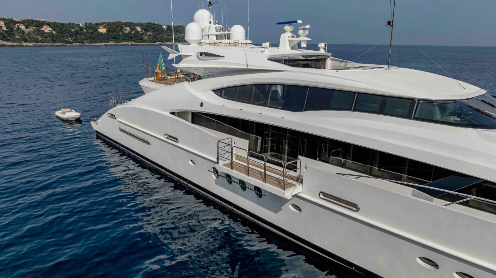 A sleek, modern yacht is anchored in calm waters with a tender nearby. aboard PALMER JOHNSON 150 Yacht for Sale