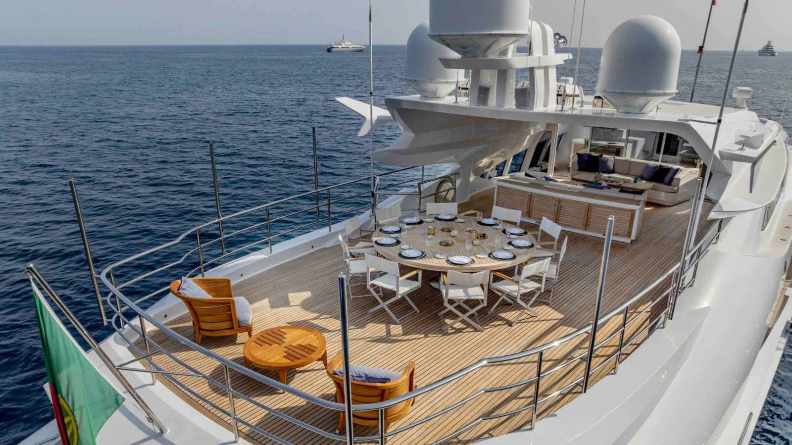The aft deck features a spacious dining area with a large table and comfortable seating, perfect for alfresco meals with a view of the sea. aboard PALMER JOHNSON 150 Yacht for Sale