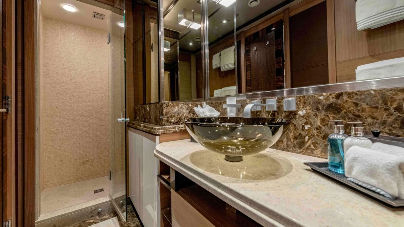 The yacht's bathroom features a luxurious glass sink and a spacious shower area with elegant marble accents. aboard PALMER JOHNSON 150 Yacht for Sale
