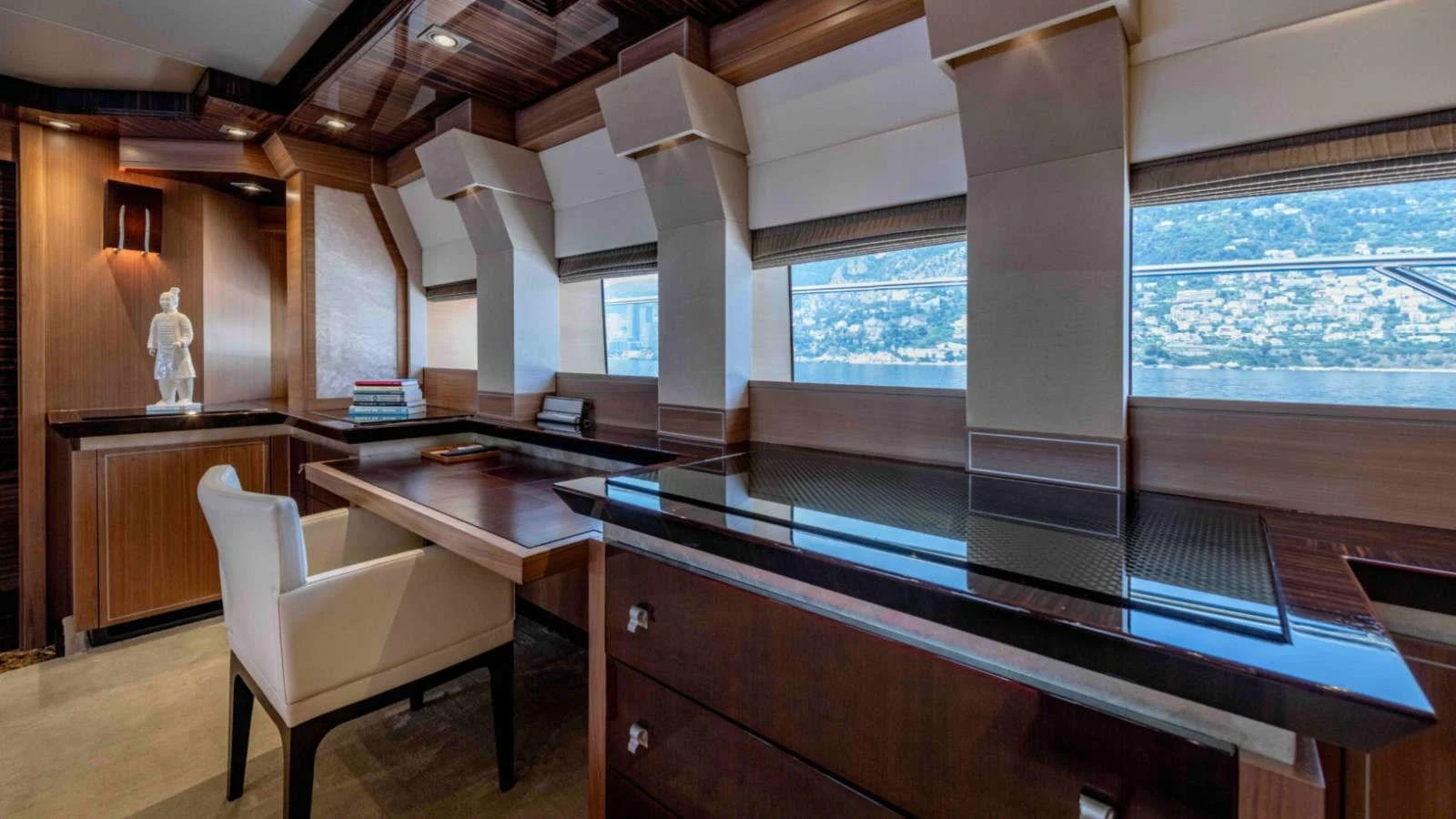 The yacht's office features elegant wood finishes, a sleek desk, and large windows offering a scenic view. aboard PALMER JOHNSON 150 Yacht for Sale