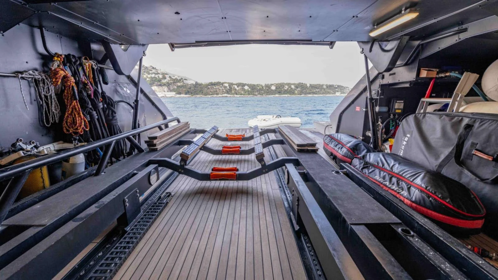 The yacht's tender garage is equipped with storage and launching mechanisms, offering a view of the water beyond. aboard PALMER JOHNSON 150 Yacht for Sale