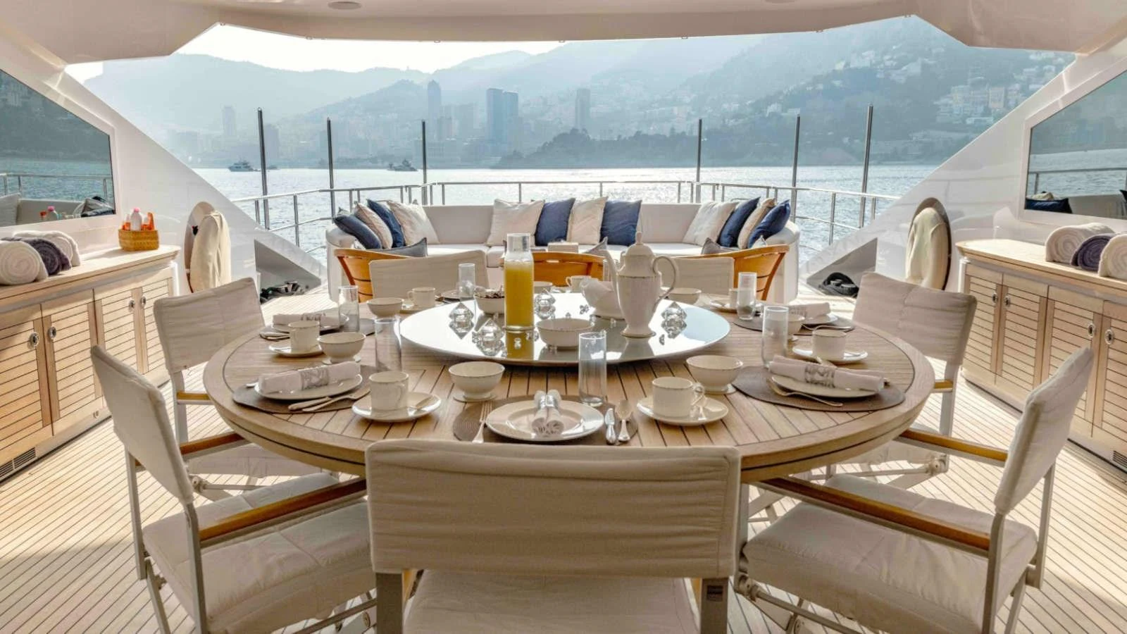 An elegant aft deck dining area with a round table set for breakfast, offering stunning views of the surrounding landscape. aboard PALMER JOHNSON 150 Yacht for Sale