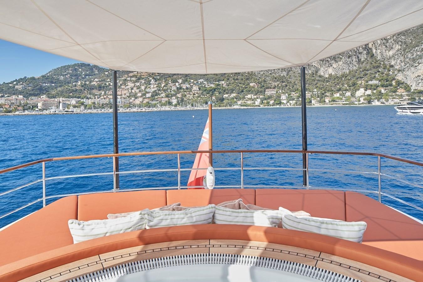 a boat with a red and white striped canopy on a blue body of water with a city in aboard SOLEMATES V Yacht for Sale