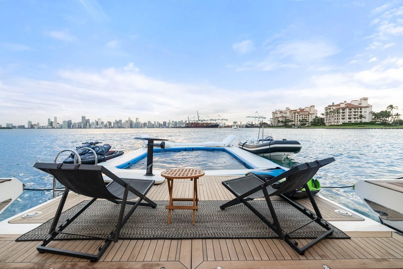a deck with a chair and a table and a pool of water aboard Y Yacht for Sale
