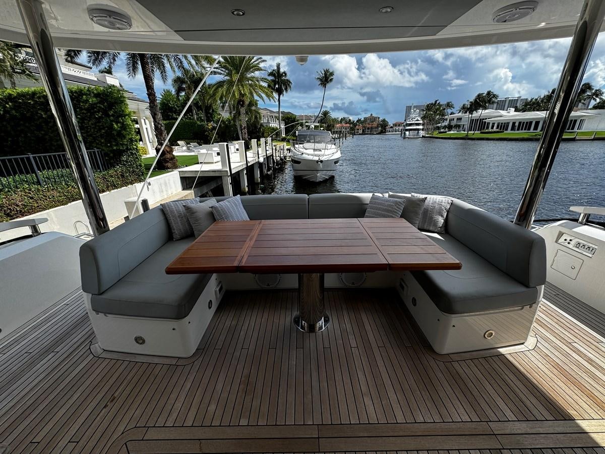 a table and a couch on a deck by a body of water aboard JOURNEY Yacht for Sale