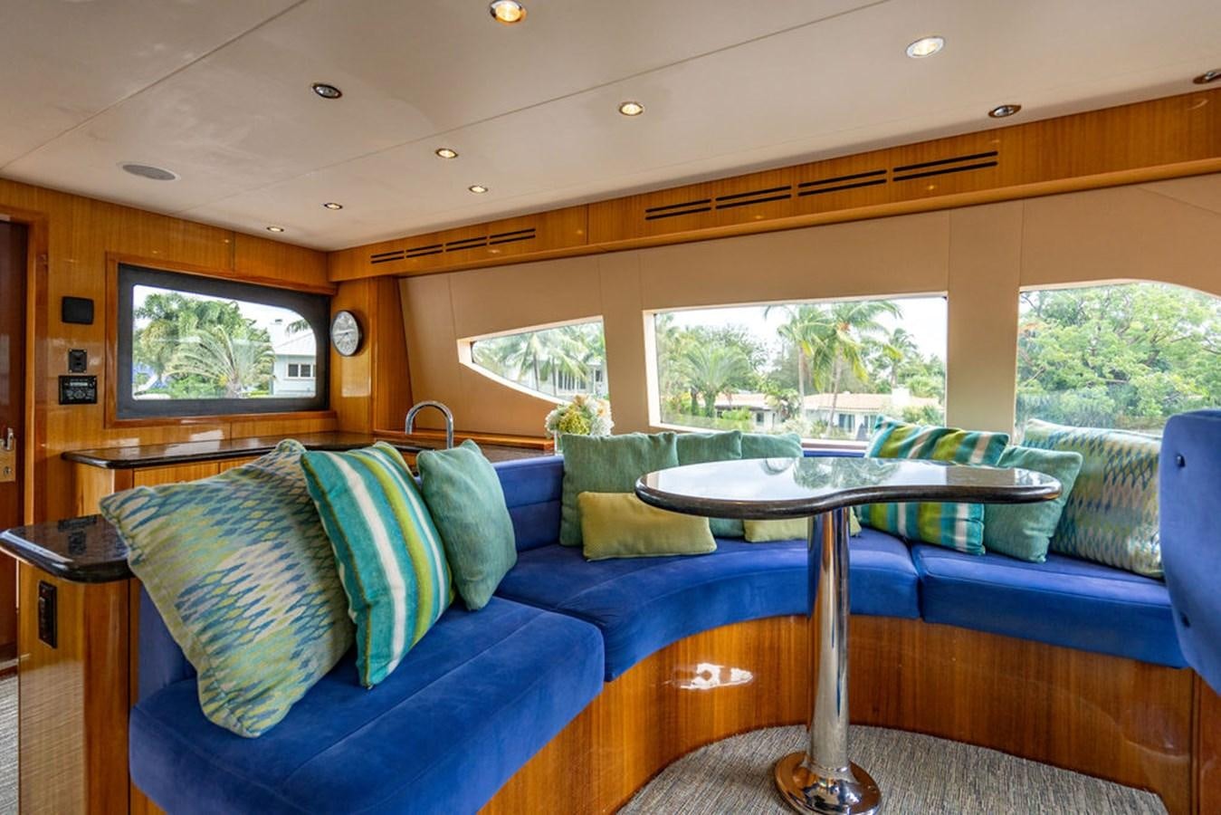 a couch with pillows and a table in a room with a window aboard TOP SHELF Yacht for Sale