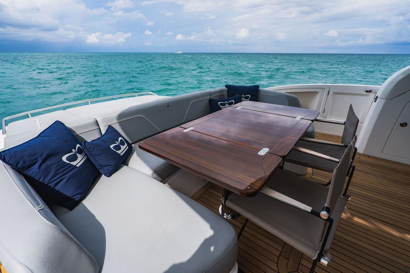 a deck with chairs and a table on it by the ocean aboard IMAGINE Yacht for Sale