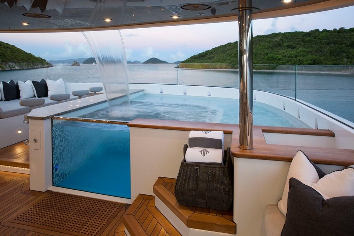 a room with a pool and a deck with a view of the water aboard MUCHOS MAS Yacht for Sale
