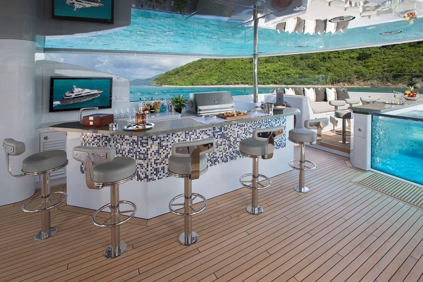 a table with stools and stools on a deck aboard MUCHOS MAS Yacht for Sale