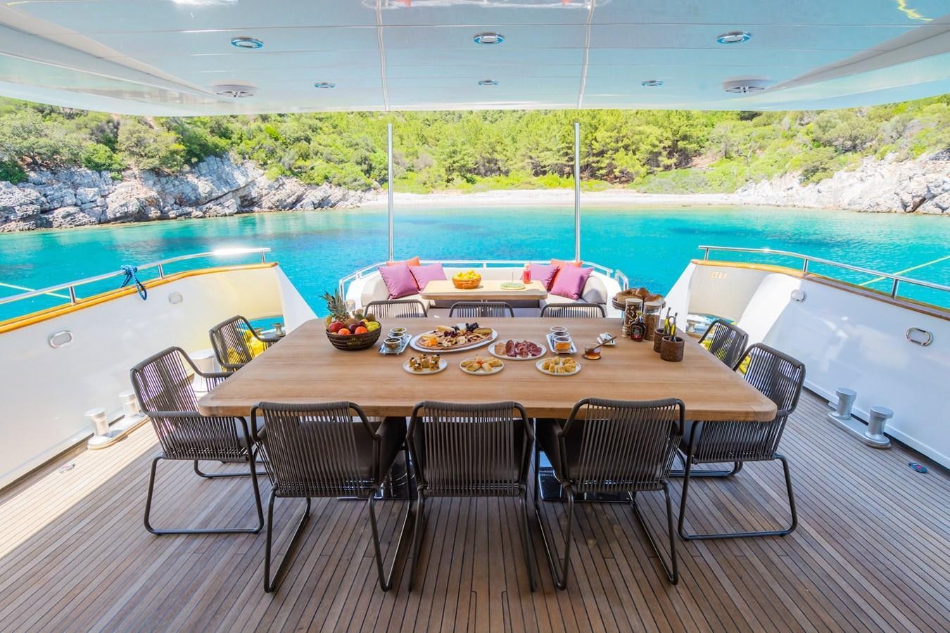 a table set for a meal on a deck overlooking a swimming pool aboard AXELLA Yacht for Sale