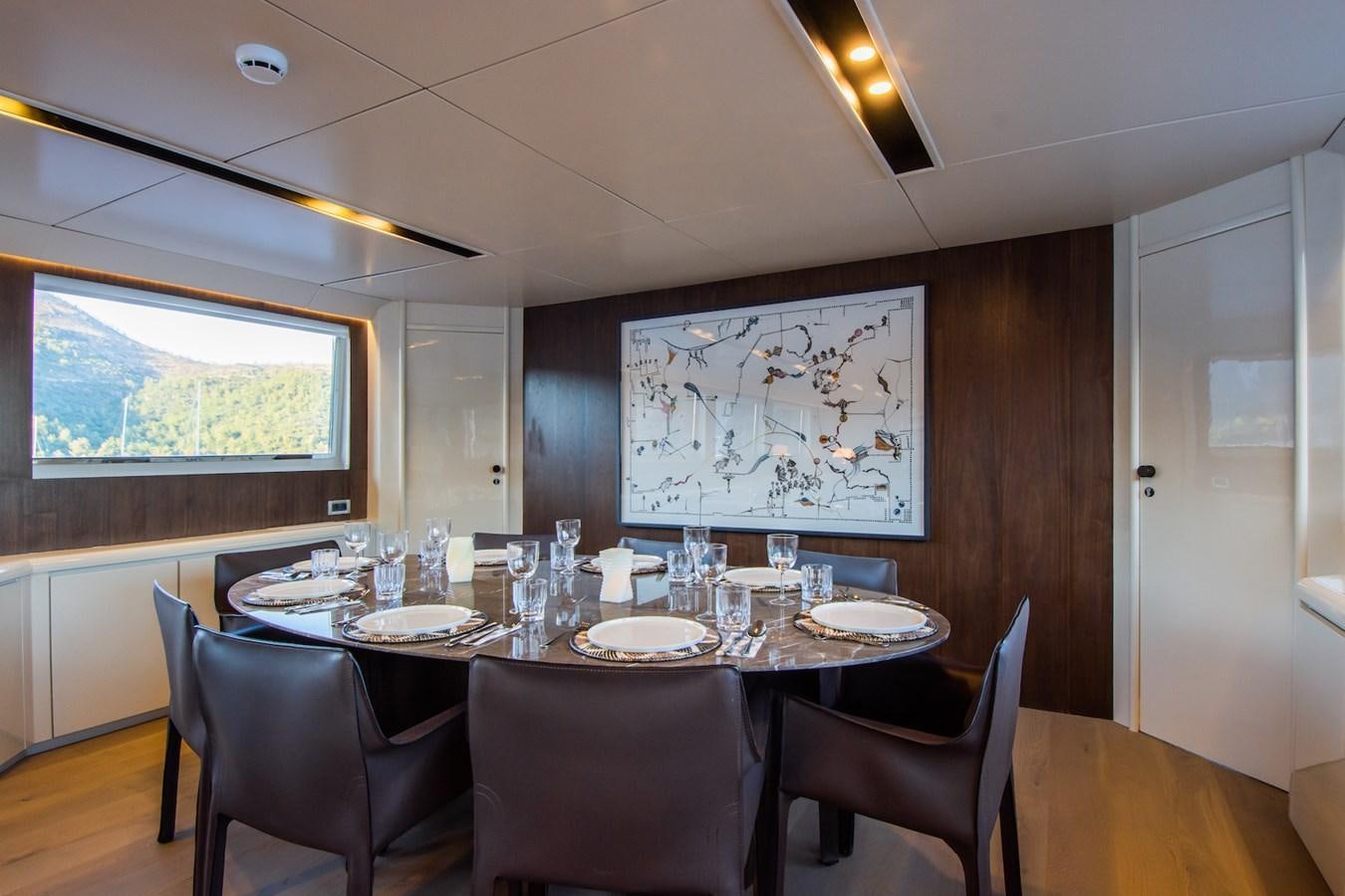a dining table with chairs and a large painting on the wall aboard AXELLA Yacht for Sale