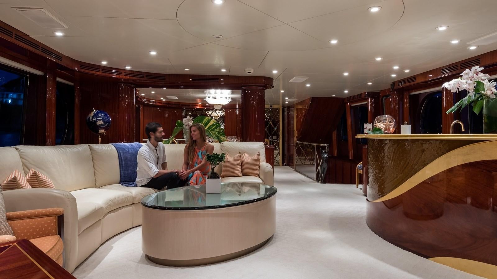 a man and woman sitting on a couch in a living room aboard TOUCH Yacht for Sale