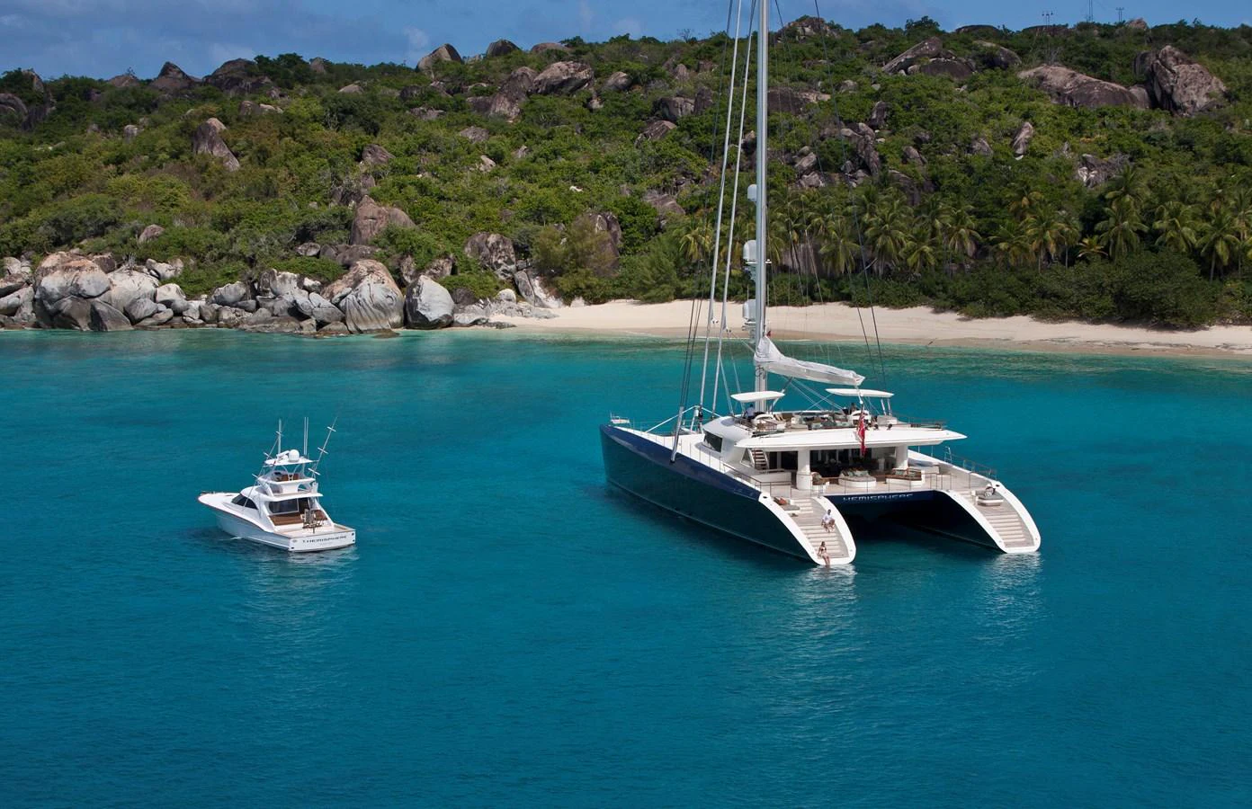 A sleek catamaran yacht anchored in a serene tropical bay with a tender nearby. aboard HEMISPHERE Yacht for Sale