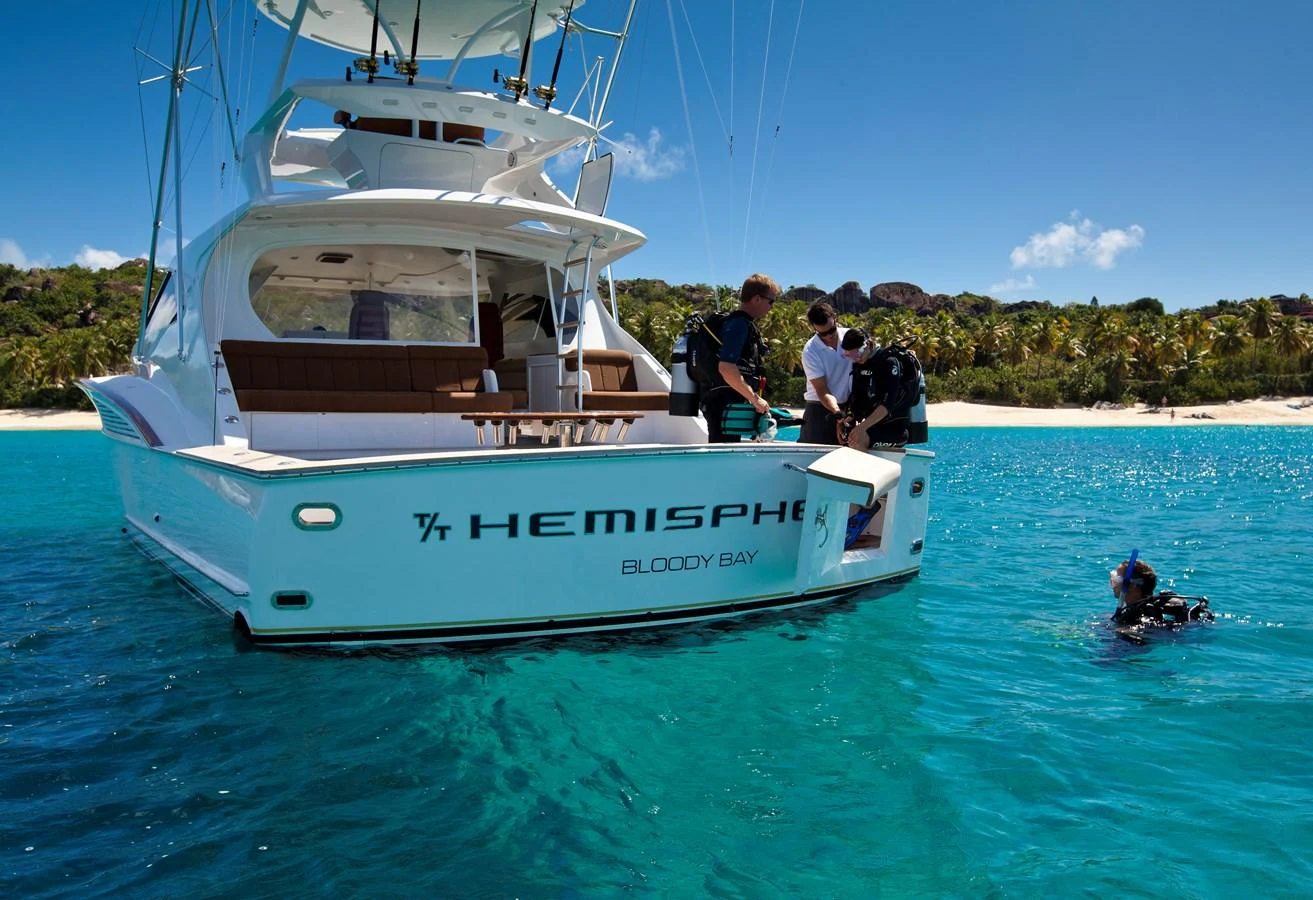 A luxurious yacht anchored in clear blue waters with people preparing for a dive. aboard HEMISPHERE Yacht for Sale